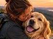 Une femme embrasse son Golden Retriever lors d'une promenade en pleine nature, illustrant le bonheur d'avoir un chien.