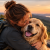 Une femme embrasse son Golden Retriever lors d'une promenade en pleine nature, illustrant le bonheur d'avoir un chien.